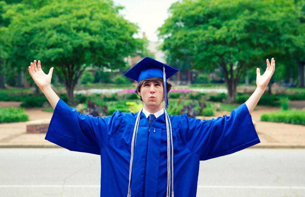 graduate in blue cap and gown celebrating with raised arms, representing completion of an online undergraduate programme