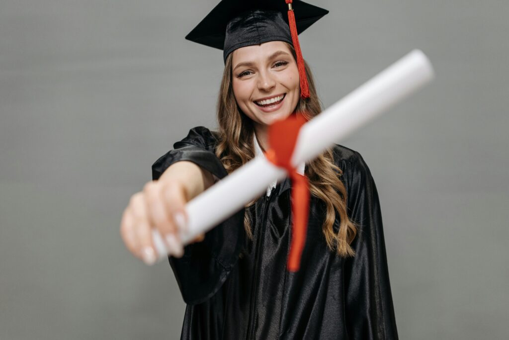 postgraduate student in graduation cap showing her certificate