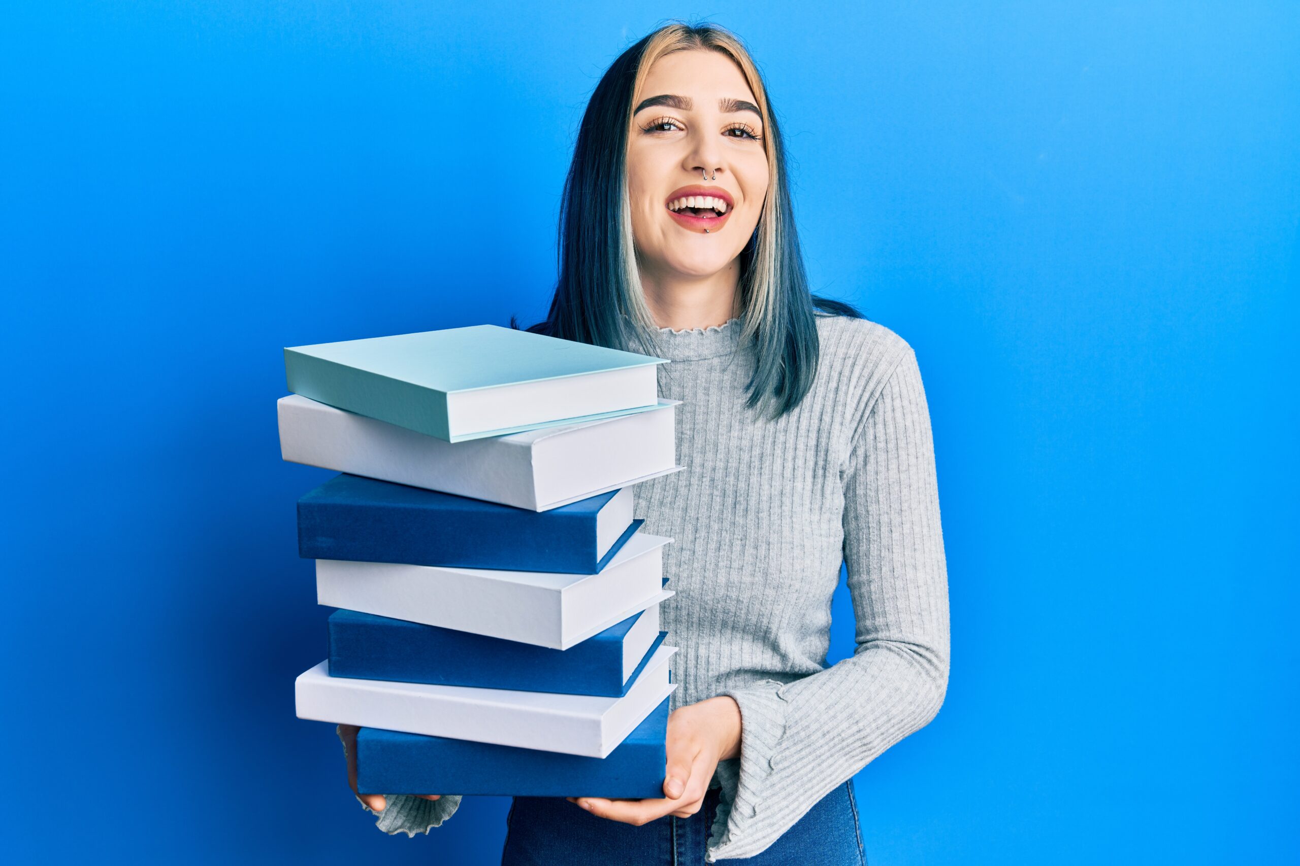 young modern girl holding a pile of books smiling and laughing hard out loud because she done ai course and upgrad her skills